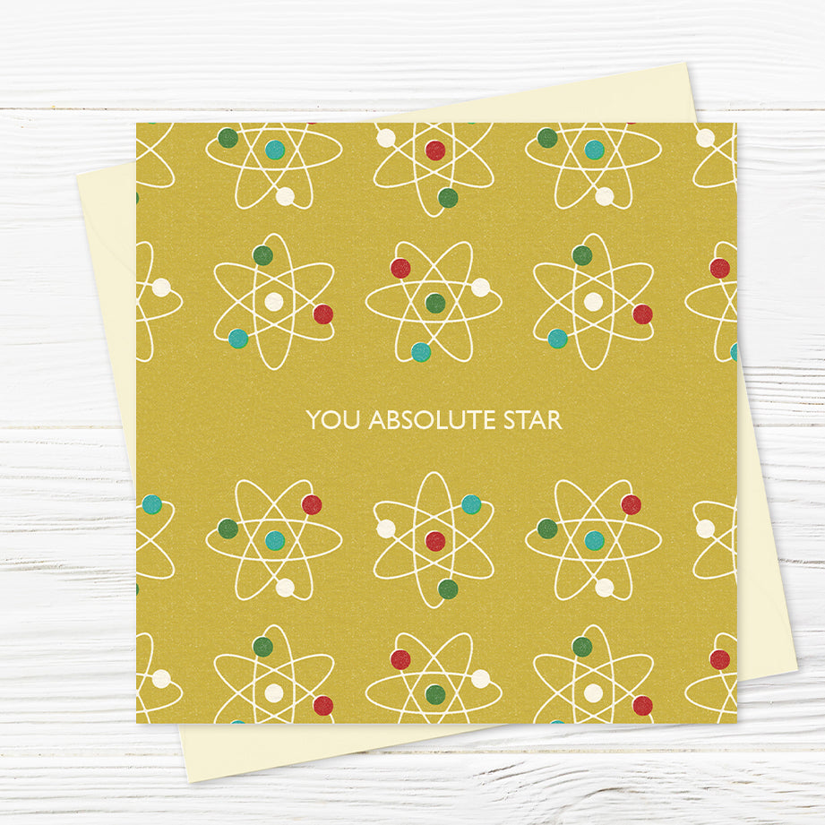 A greetings card from the Festival Hall range that features a repeat pattern of atomic stars in primnary colours on a mustard background with the words 'you absolute star' across the middle. 