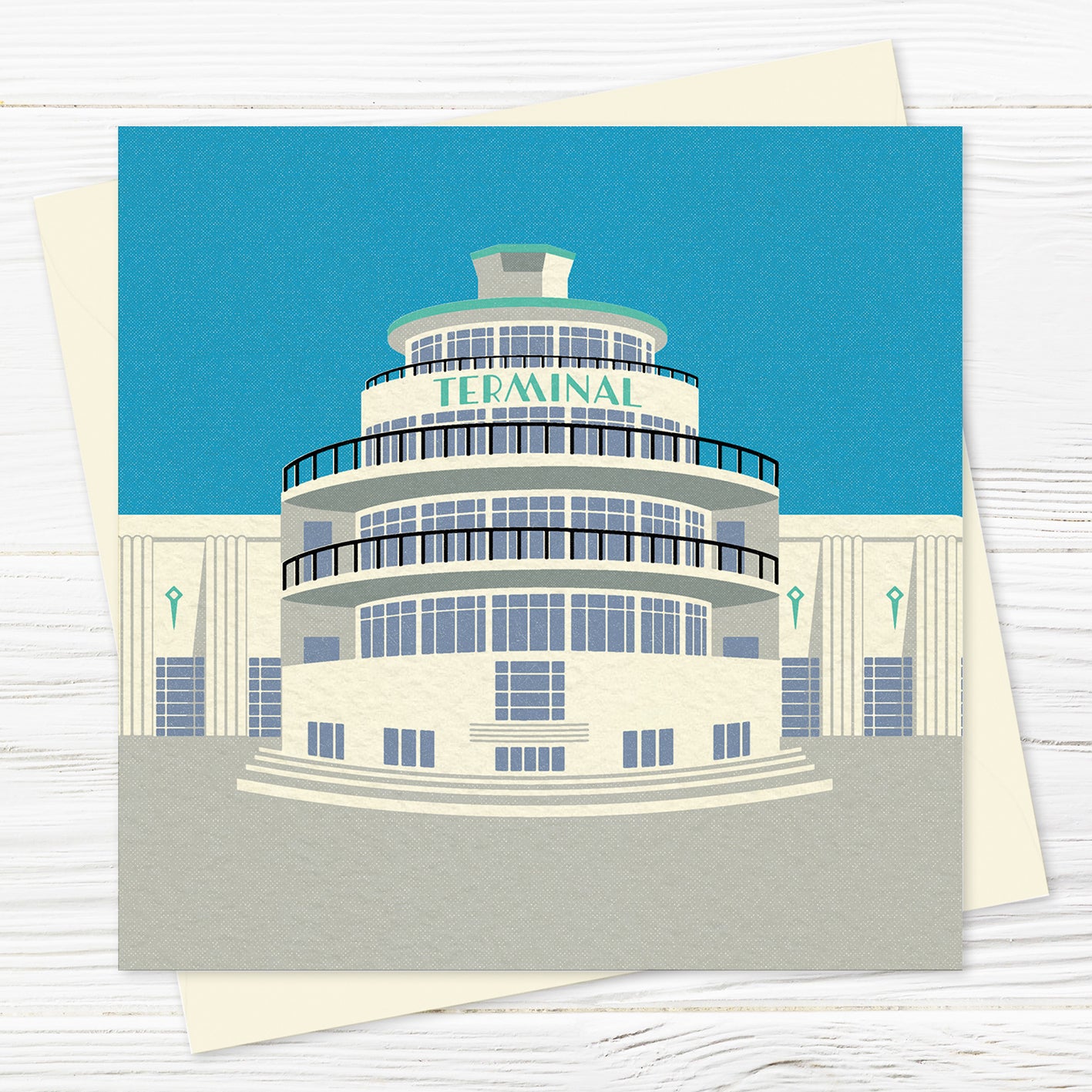 A  greetings card and envelope featuring a stylised illustration of an circular art deco airport building in blue, grey and green with the word 'terminal' across the front of the building.